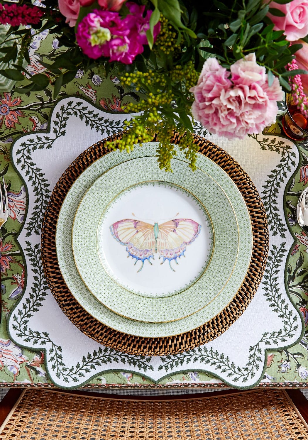 A delicate mint green ceramic plate with a painted butterfly on brown woven placemat from tabitha green wreath placemats