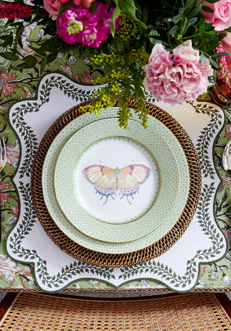 A delicate mint green ceramic plate with a painted butterfly on brown woven placemat from tabitha green wreath placemats