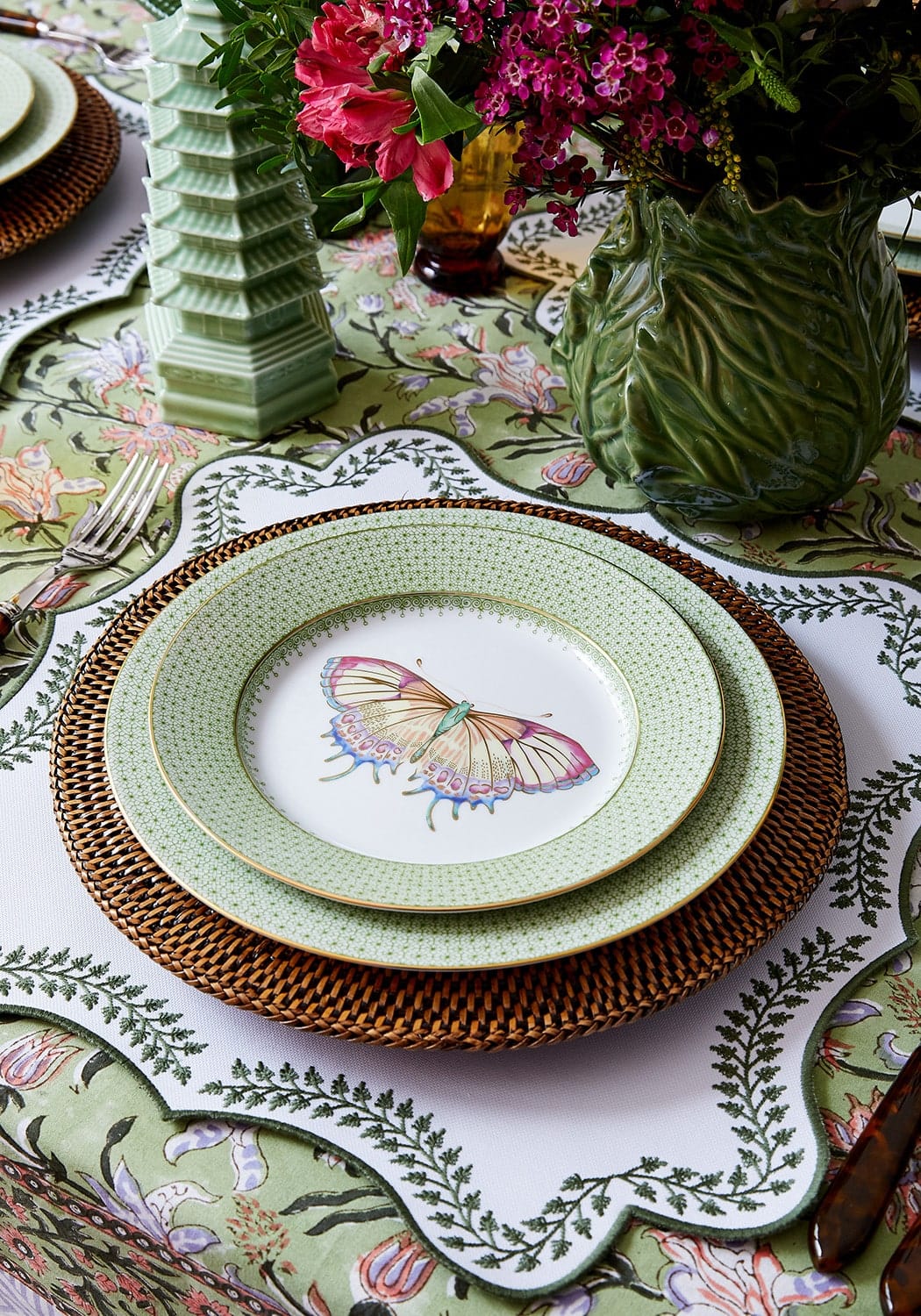 A delicate mint-green ceramic plate with a pink butterfly on woven brown placemat from tabitha green wreath placemats set