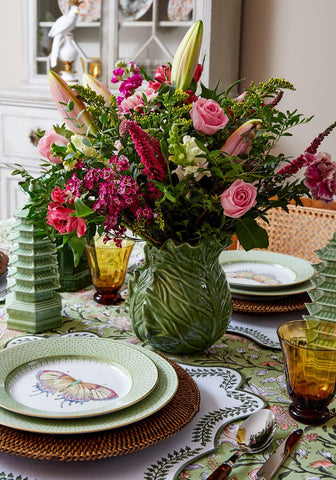 A vibrant green ceramic vase with pink roses complements the tabitha green wreath placemats set of 4