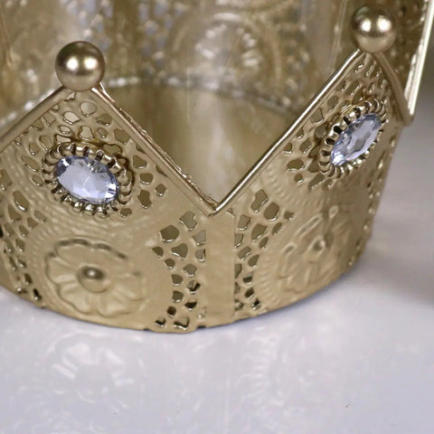 Gold-colored metal talika crown candle holder with intricate cut-out patterns and blue gemstone accents
