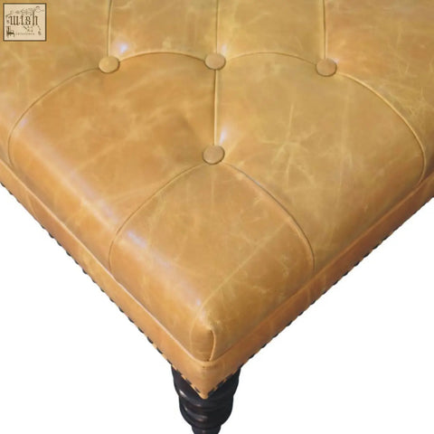Tan leather upholstered ottoman with tufted button detailing and dark wooden legs for stylish seating or storage