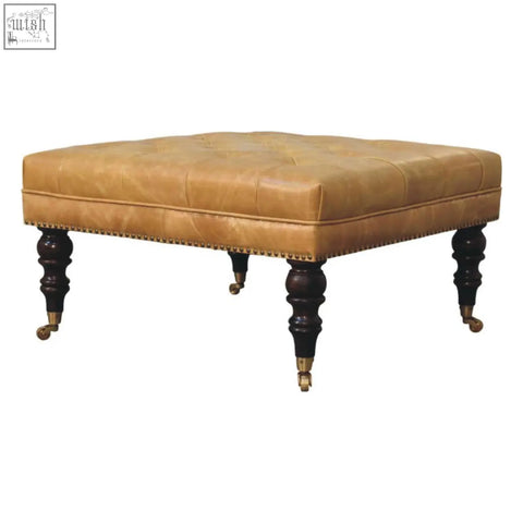 Tan leather upholstered ottoman with tufted top dark wood legs and brass casters perfect for living room seating