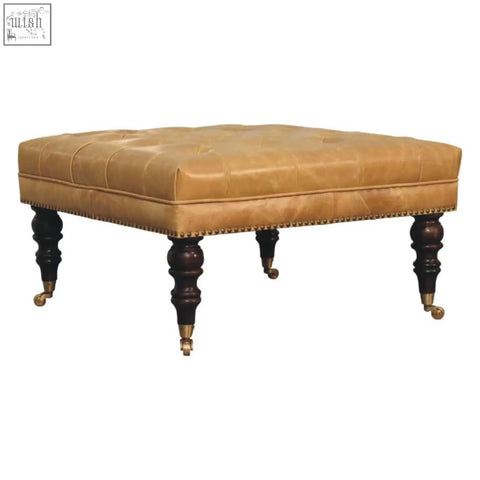 Tan leather upholstered ottoman with tufted top dark wood legs and brass casters for stylish seating or storage