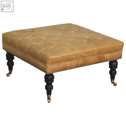 Tan leather upholstered ottoman with tufted top dark wood legs and brass casters for stylish living room seating