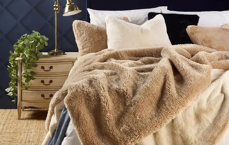 Tan plush throw blanket with a soft, fuzzy texture and neutral color scheme.
