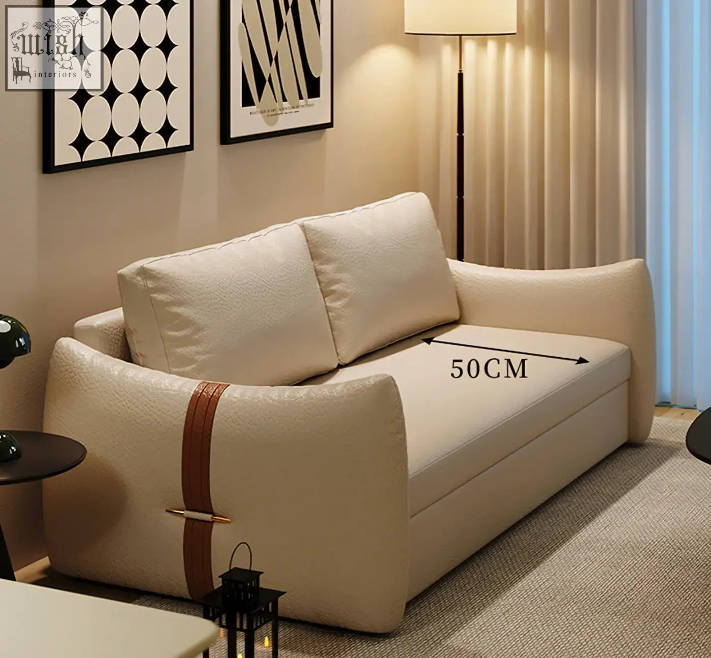 Cream upholstered tanak two seater sofa bed with brown leather strap accent and gold hardware in leathaire