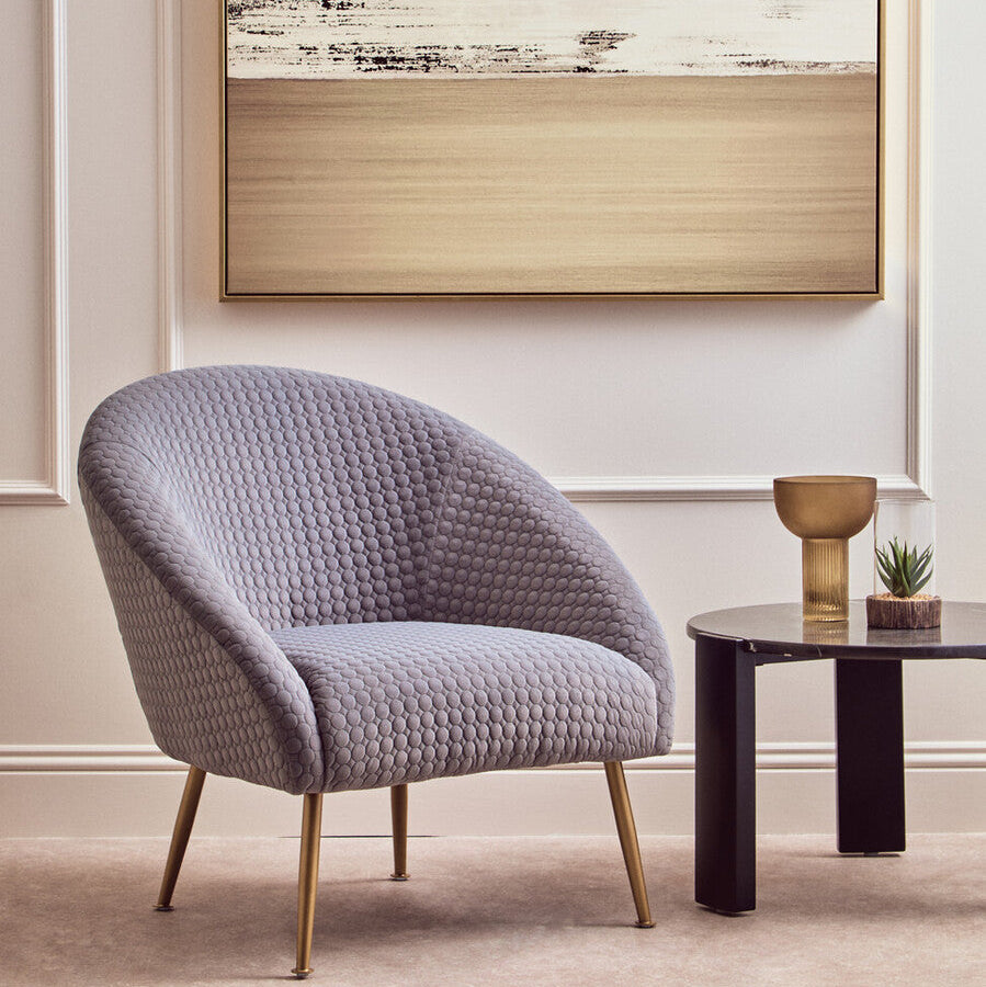 A plush tania grey occasional chair with light grey honeycomb upholstery and slim gold metal legs perfect for any room