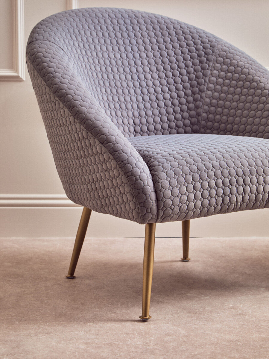 A sleek tania grey occasional chair with quilted grey upholstery and gold-tone metal legs for stylish seating