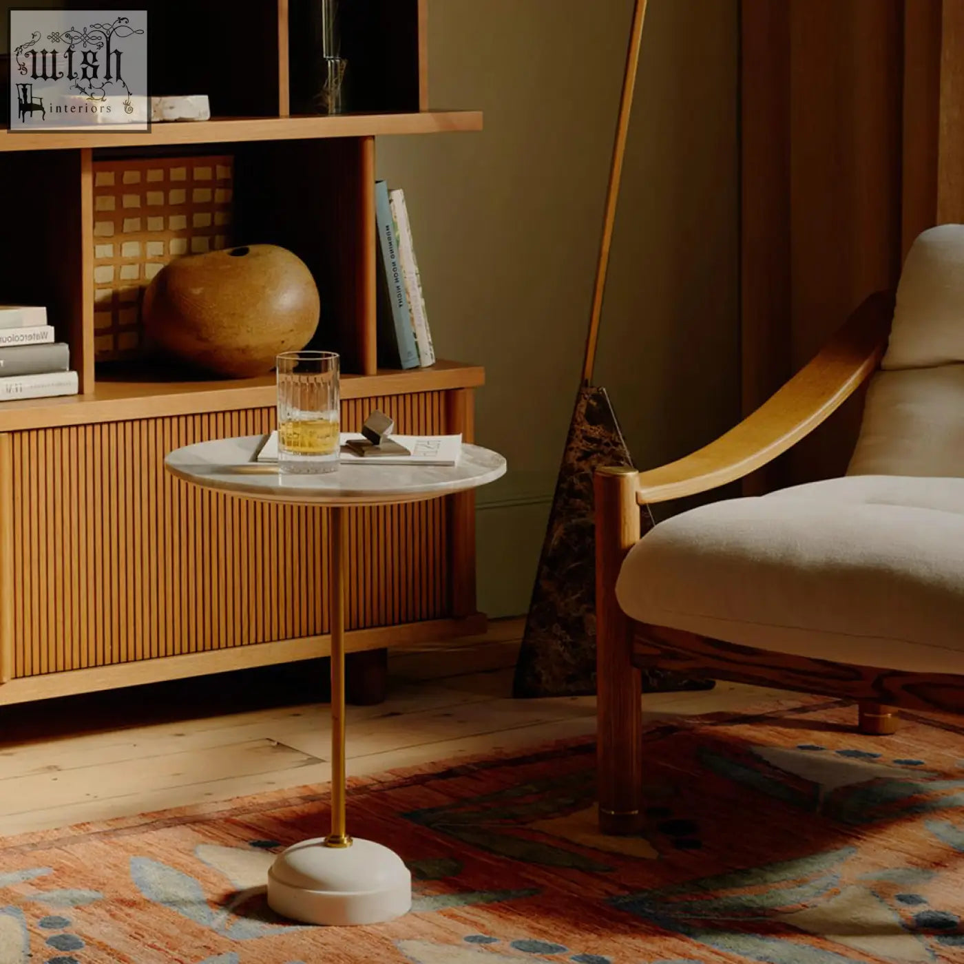 A sleek tarantino side table with a white marble top and slender gold toned stainless steel legs