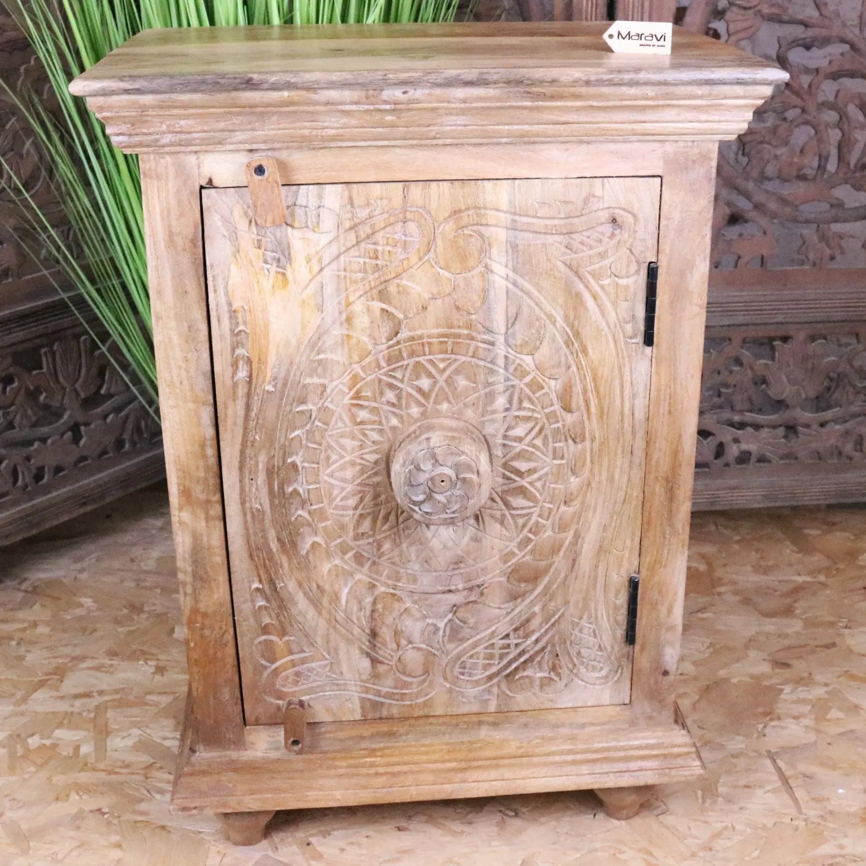 Tarinda carved wooden storage cabinet with hand carved circular floral patterns natural light wood finish and black hinges