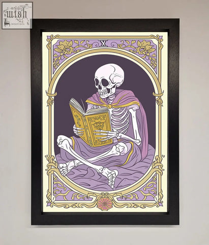A framed print of a tarot skeleton reader in a purple robe holding an ornate book with gold and lavender floral border