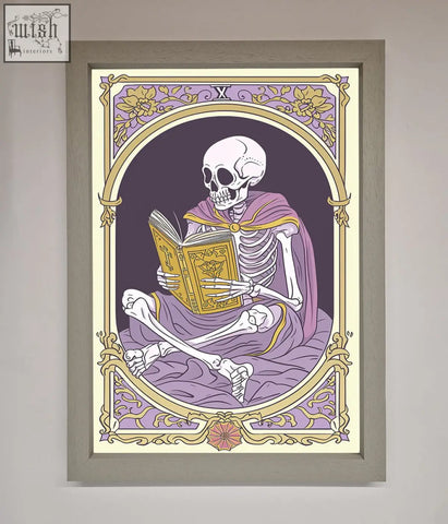 A framed print of a tarot skeleton reader in a purple robe holding a golden book within an ornate arched border