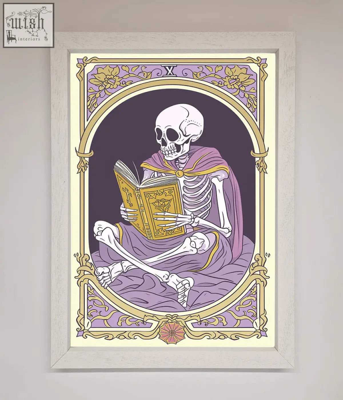 A framed print featuring a tarot skeleton reader in a purple robe holding an ornate golden book in a decorative border