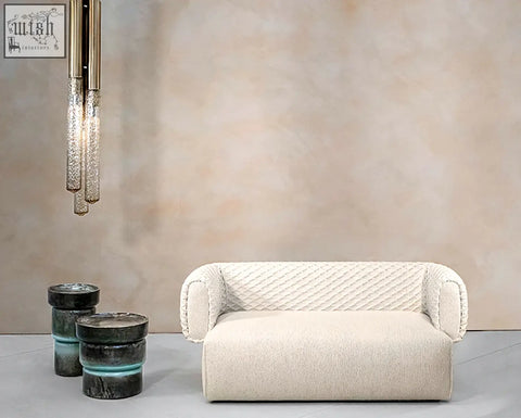 Cream-colored plush quilted two seater sofa with soft textured fabric and rounded armrests offer financing available