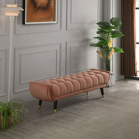 A plush tb15 orange bench with rose gold velvet tufted upholstery and dark wood legs with brass caps