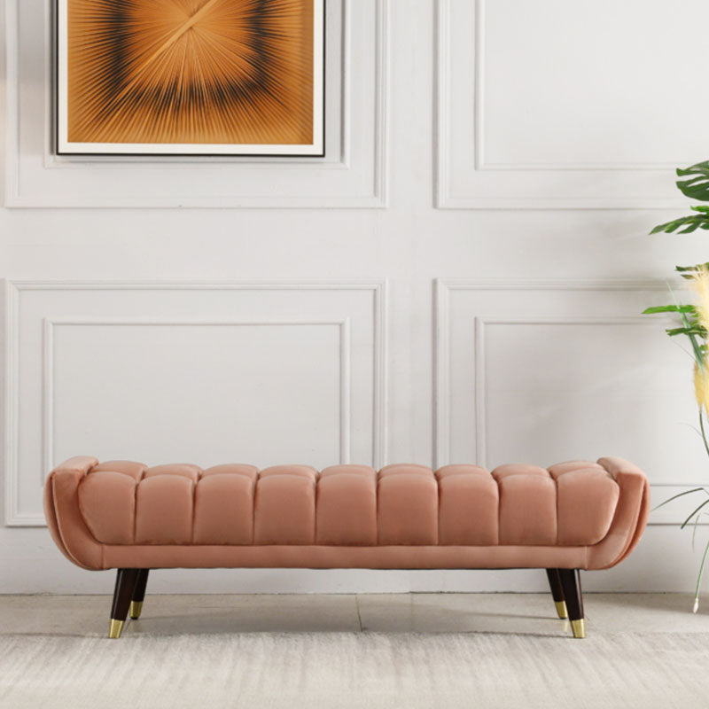 A plush rose-pink velvet tb15 orange bench with tufted upholstery and dark wood tapered legs with gold tips