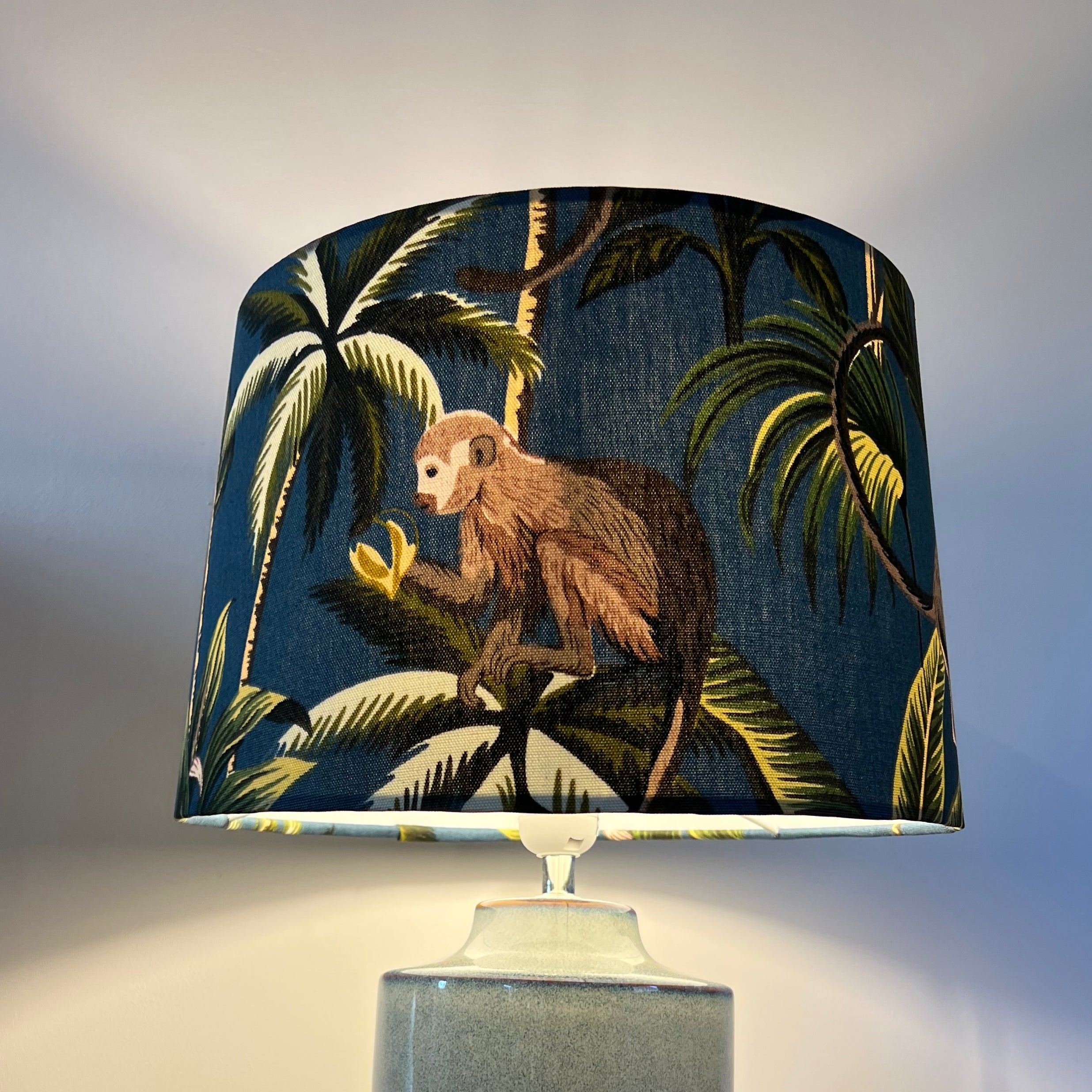 Navy blue french drum lampshade with jungle monkey cotton design featuring a brown monkey and palm trees