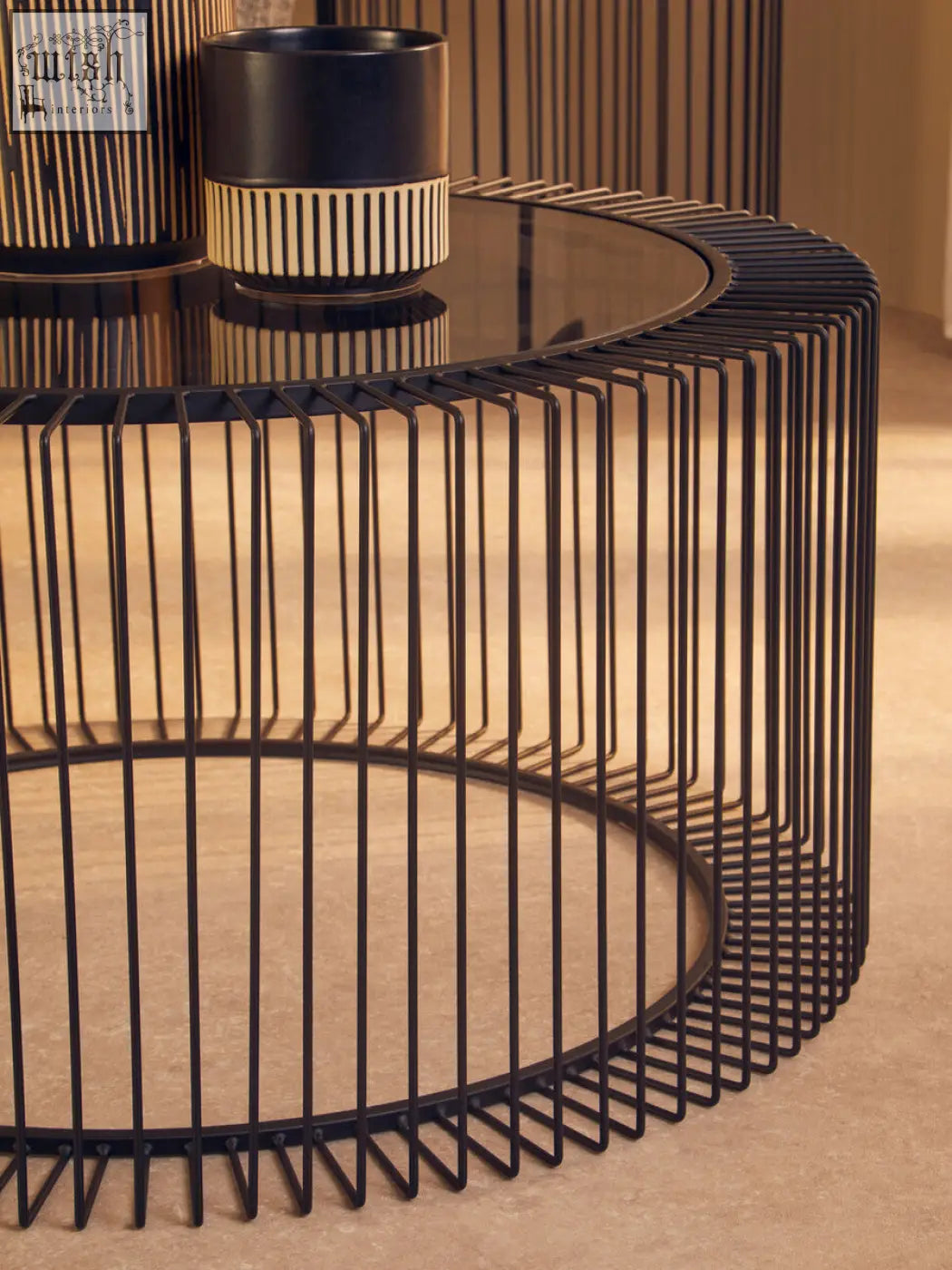 Modern round coffee table with black wireframe cage base and tempered glass top for stylish living spaces