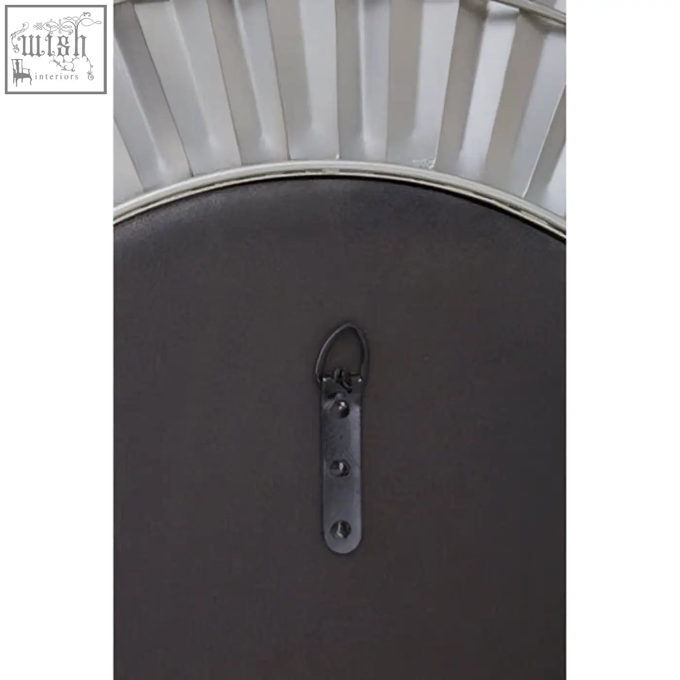 The back of a round dark gray metal-framed sunburst wall mirror with decorative fan edges and a hanging bracket