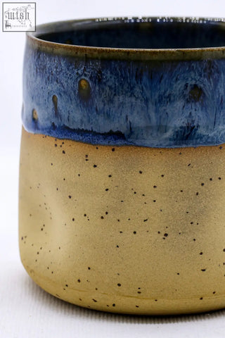 A terrablu goccia handmade ceramic stoneware cup with a speckled tan body and vibrant blue glazed rim