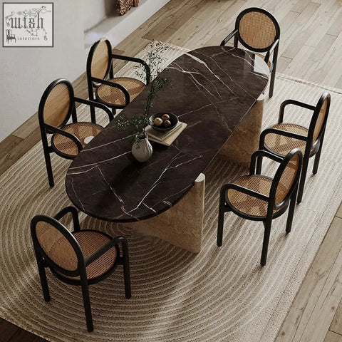 Elegant teruo dining table with dark marble top, white veining, and a sturdy base paired with black cane chairs