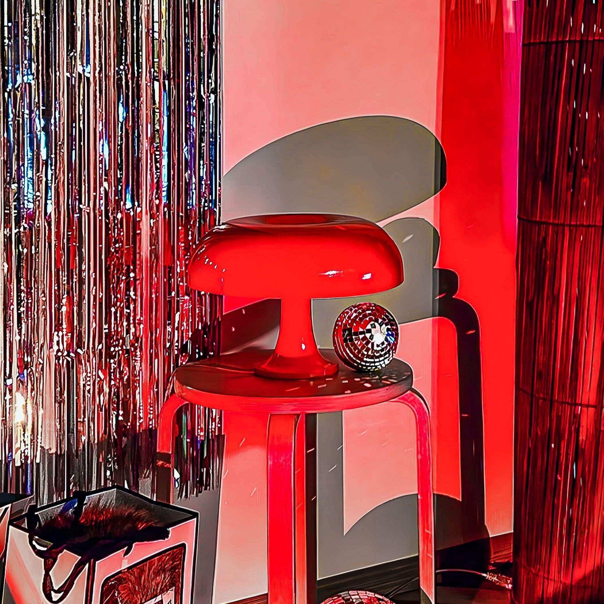 Vibrant red ambient mushroom desk lamp with glossy finish sits on matching stool for stylish ambient lighting