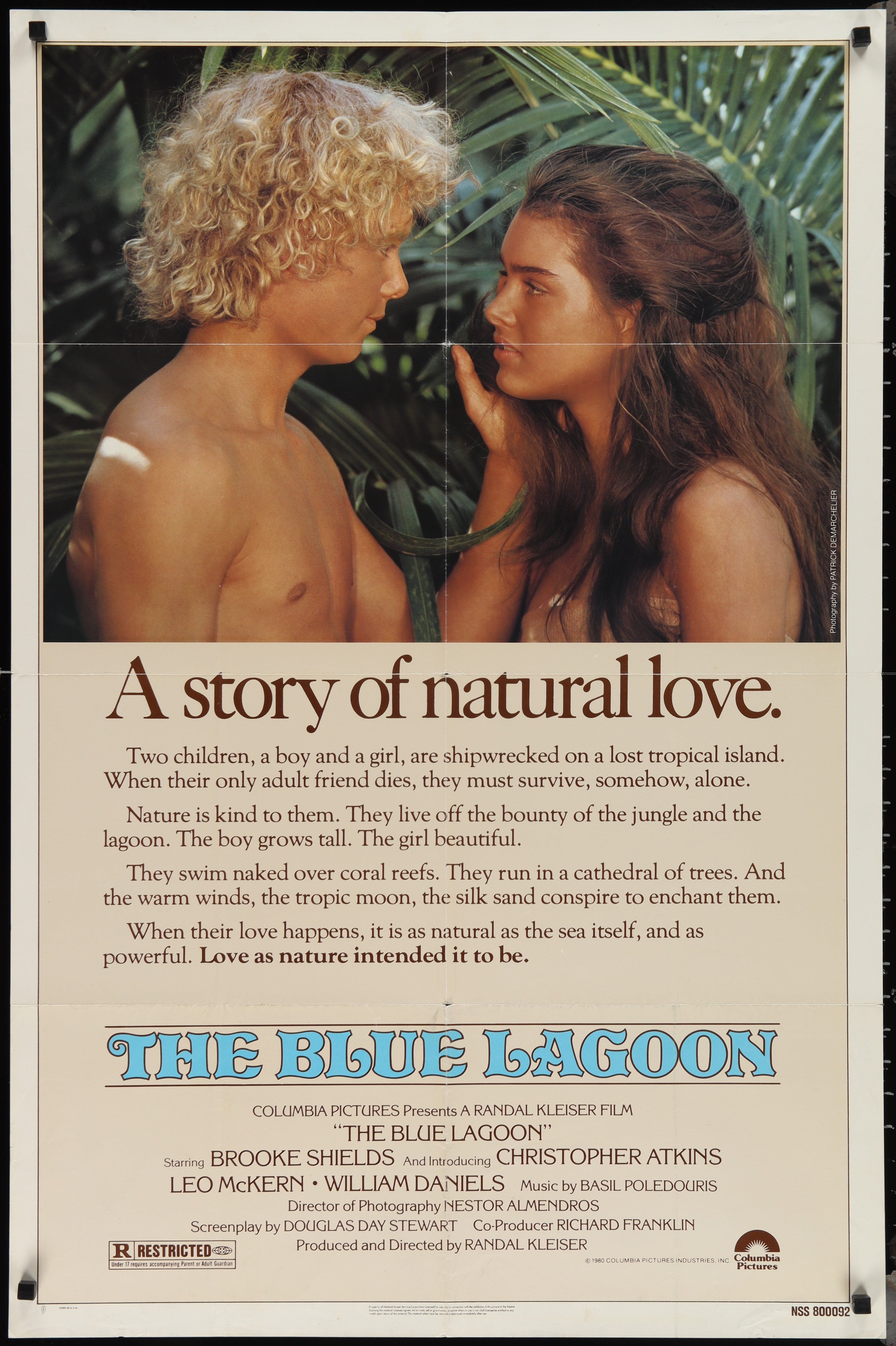 Vintage blue lagoon movie poster featuring a romantic scene of two young lovers in tropical foliage