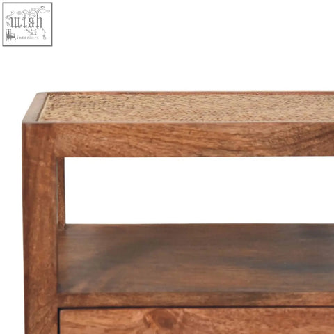 A caldera bedside stand with honey caramel finish featuring a rustic wooden frame and open shelf with woven cane top