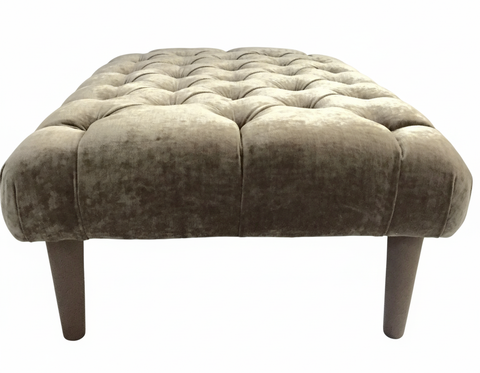 The Chester Foot Stool is a taupe velvet tufted ottoman with dark wooden legs perfect for living room seating