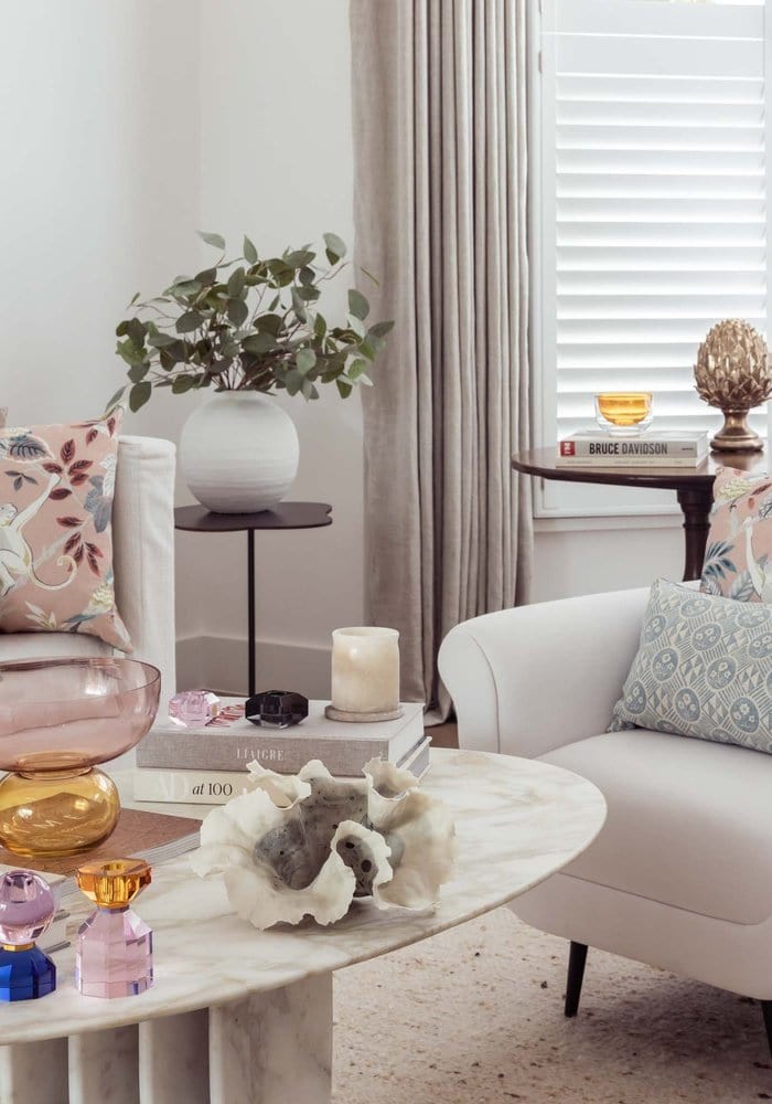 The cushion and asscher pair white marble coffee table with shell centerpiece and colorful glass candle holders