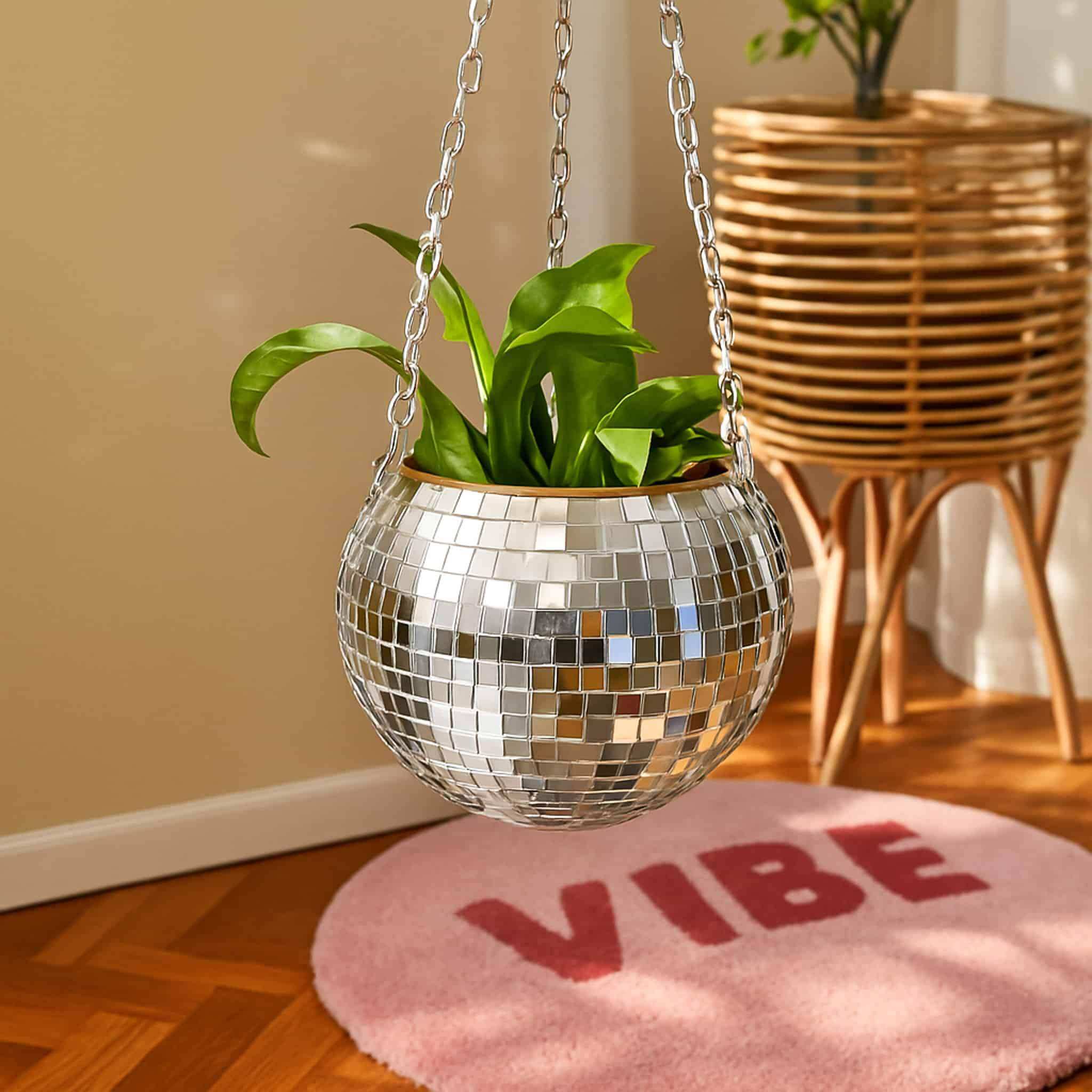 A shiny silver disco ball planter with a chain hanging green leaves in the disco planter product