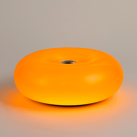 The donut lamp is a glowing orange ambient orange lamp with a smooth translucent plastic body and a metal center hole