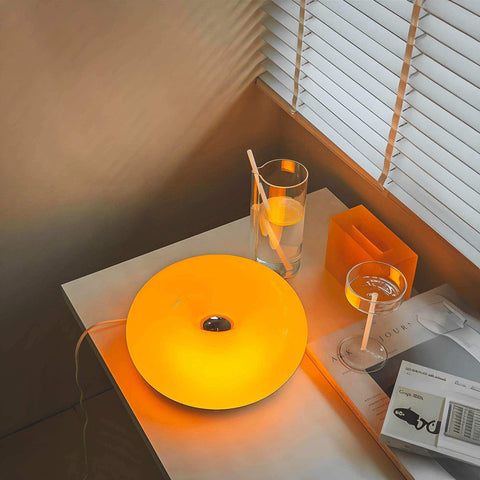 A warm ambient orange donut lamp with a smooth glossy finish and a central dark accent for cozy lighting