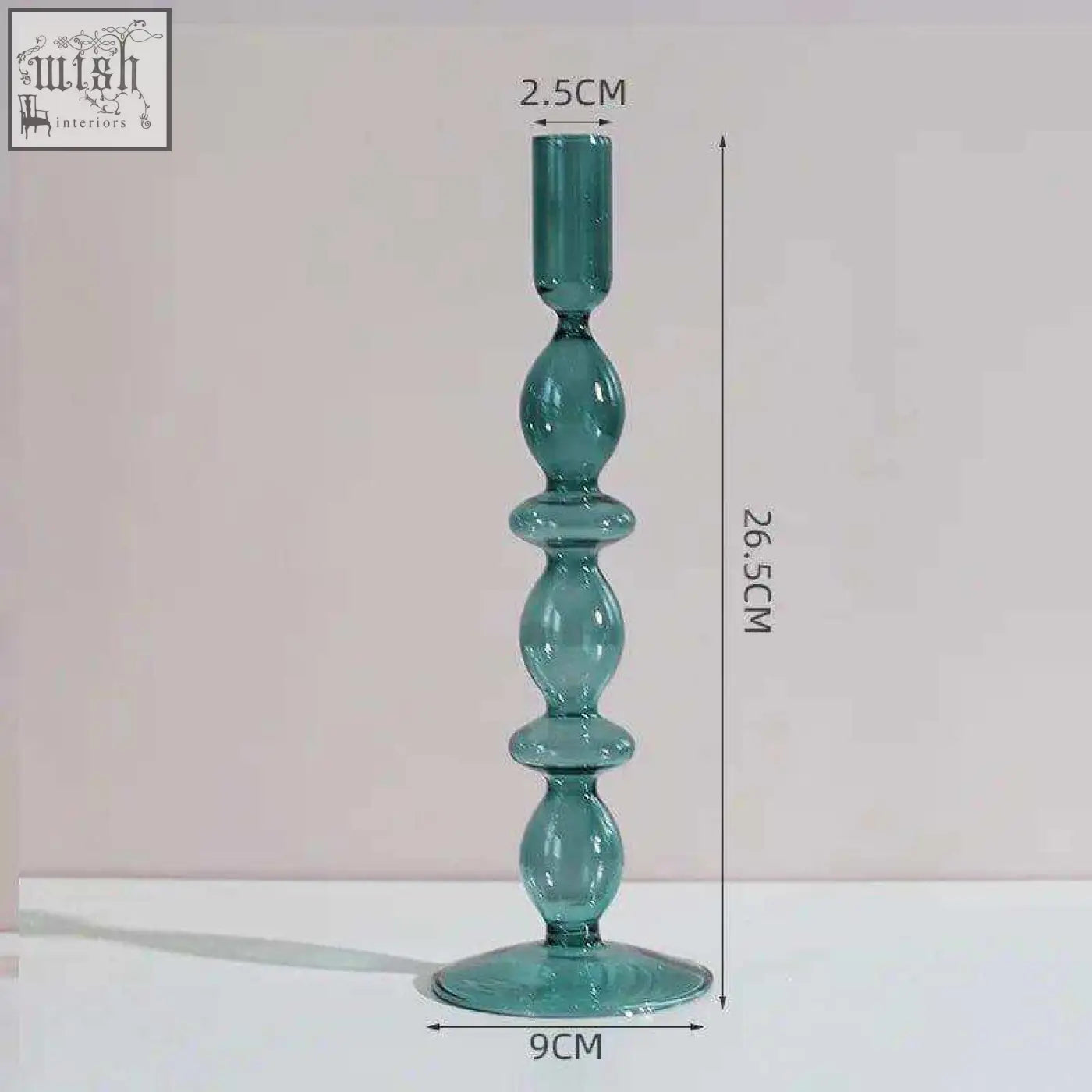 The glass candle holder is a tall teal glass candle with a slender stem and wide circular base for stability