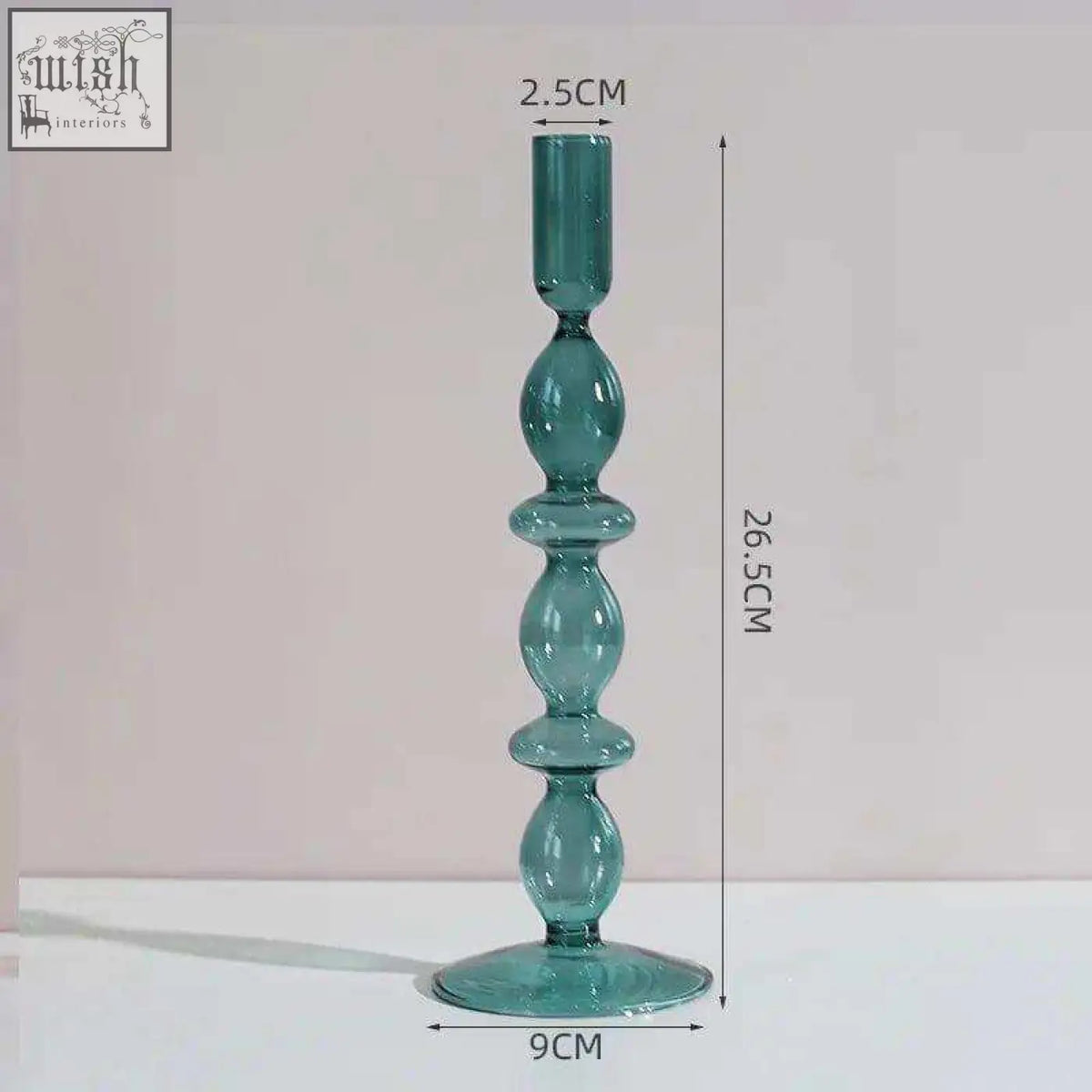 The glass candle holder is a tall teal glass candle with a slender stem and wide circular base for stability