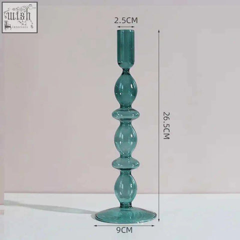 The glass candle holder is a tall teal glass candle with a slender stem and wide circular base for stability