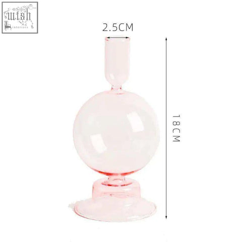 A translucent pink glass candle holder with a spherical body narrow neck and flared base for candles