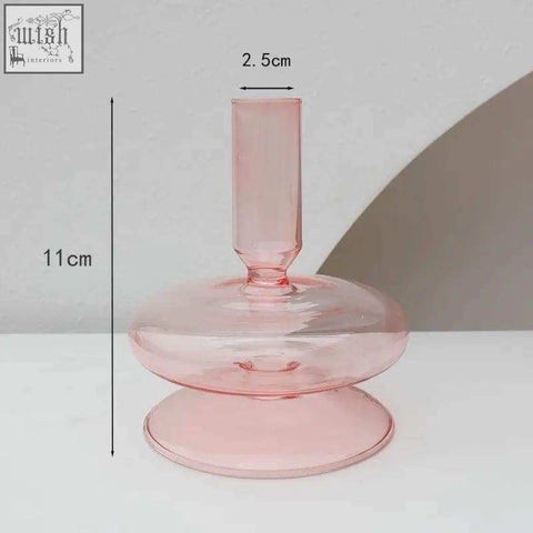 A translucent pink glass candle holder with a slender stem and wide rounded base perfect for holding glass candles