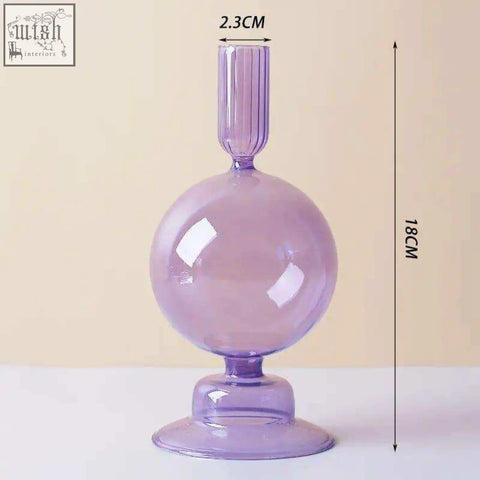 A translucent lavender glass candle holder with a spherical body fluted neck and pedestal base