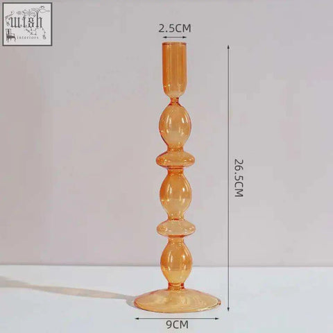 A tall translucent amber glass candle holder with a slender stem and flared base perfect for a glass candle