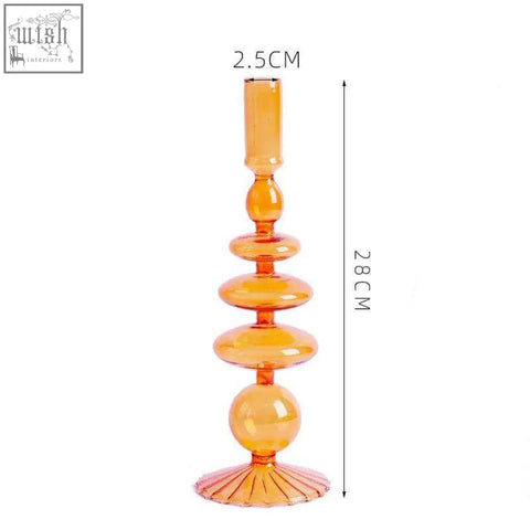 The glass candle holder is a tall amber glass candle holder with a sleek tiered design and fluted base