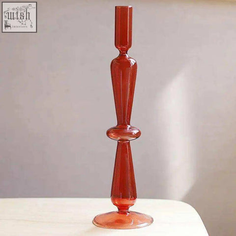 A tall translucent amber glass candle holder with a slender stem and decorative bulbous midsection