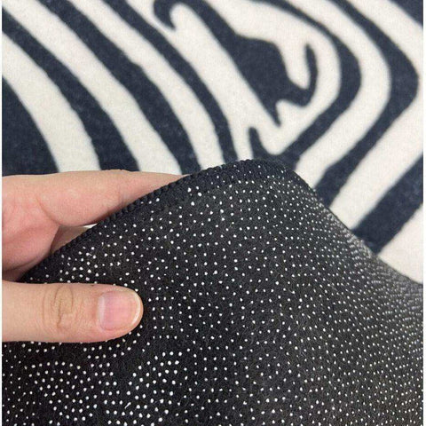 The illusion rug features black fabric with a subtle white polka dot pattern and a soft textured surface