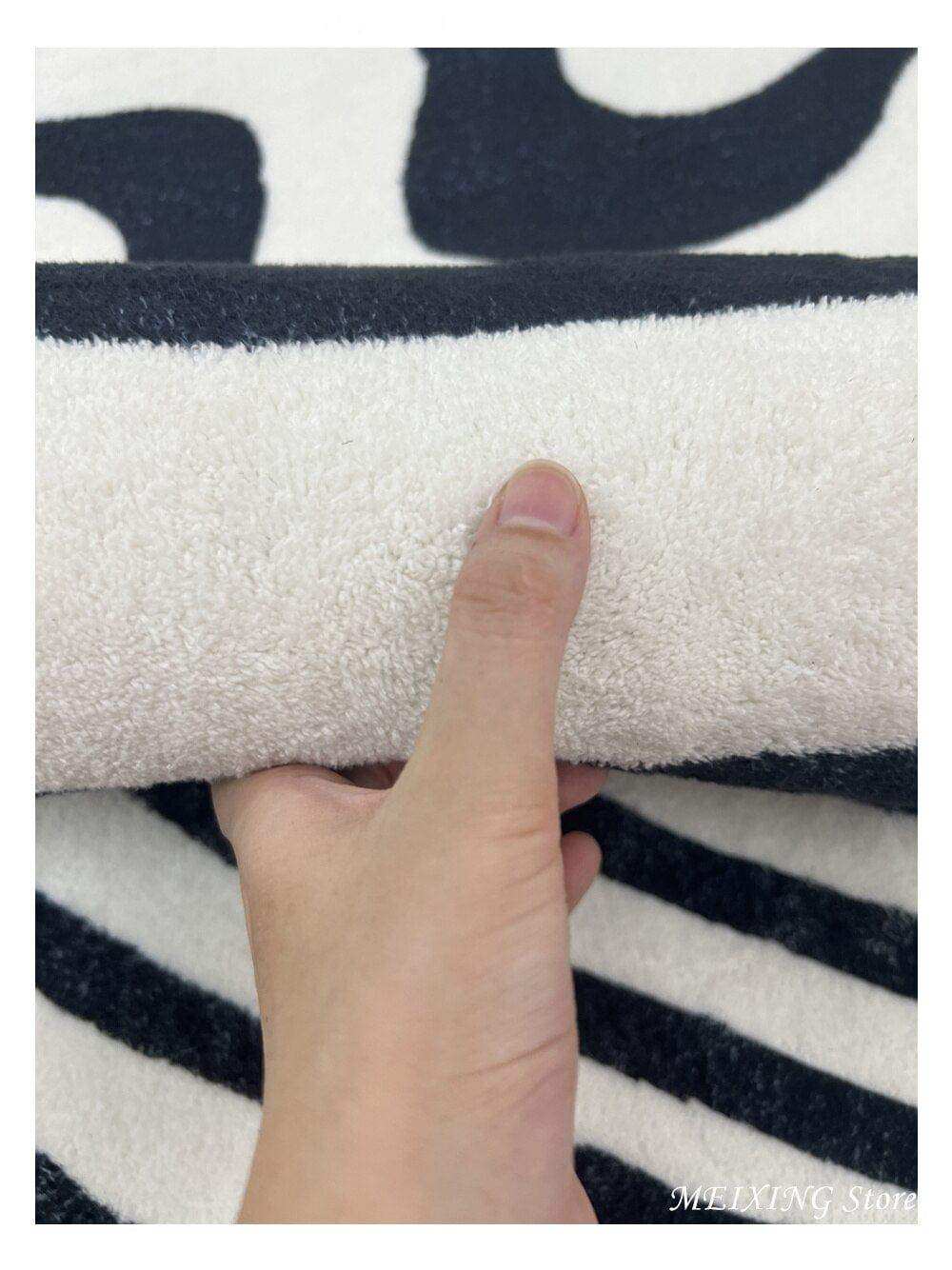 A plush cream-colored fleece blanket with bold black abstract patterns featured in the illusion rug collection