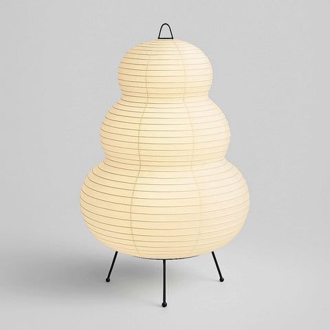 The cream-colored Japanese hikaru lamp features rice paper tiers on an iron tripod stand for soft lighting