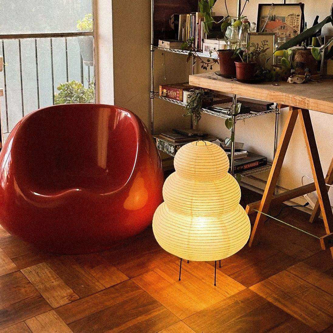 The japanese hikaru lamp glowing warm yellow tiered rice paper shade on iron tripod base