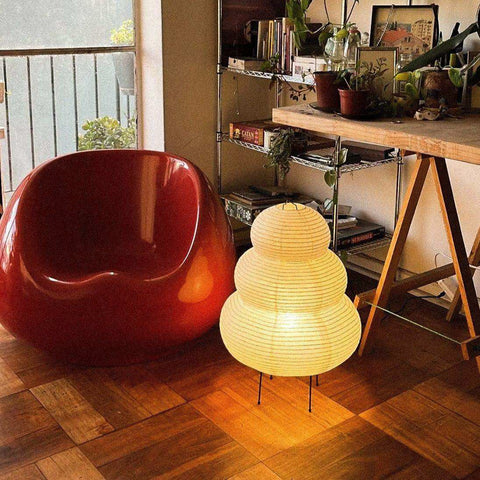 The japanese hikaru lamp glowing warm yellow tiered rice paper shade on iron tripod base