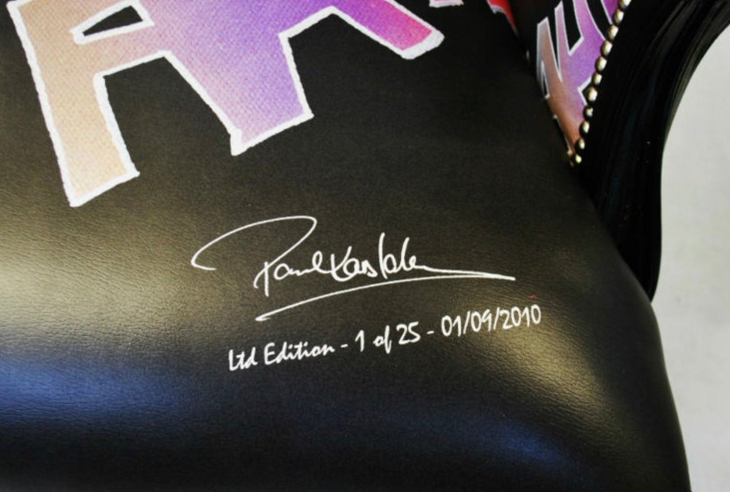 Black leather boxing glove with purple and beige r logo signed by paul krasble for the joker chair collection
