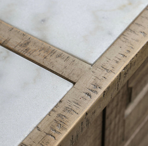 The manor kitchen island features a gold-toned metal frame with a rustic finish bordering white marble tiles